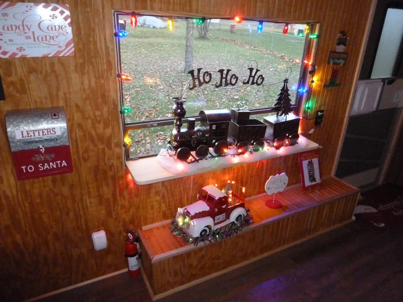 Lighted cabin window decorated with North Pole trains and Christmas signs
