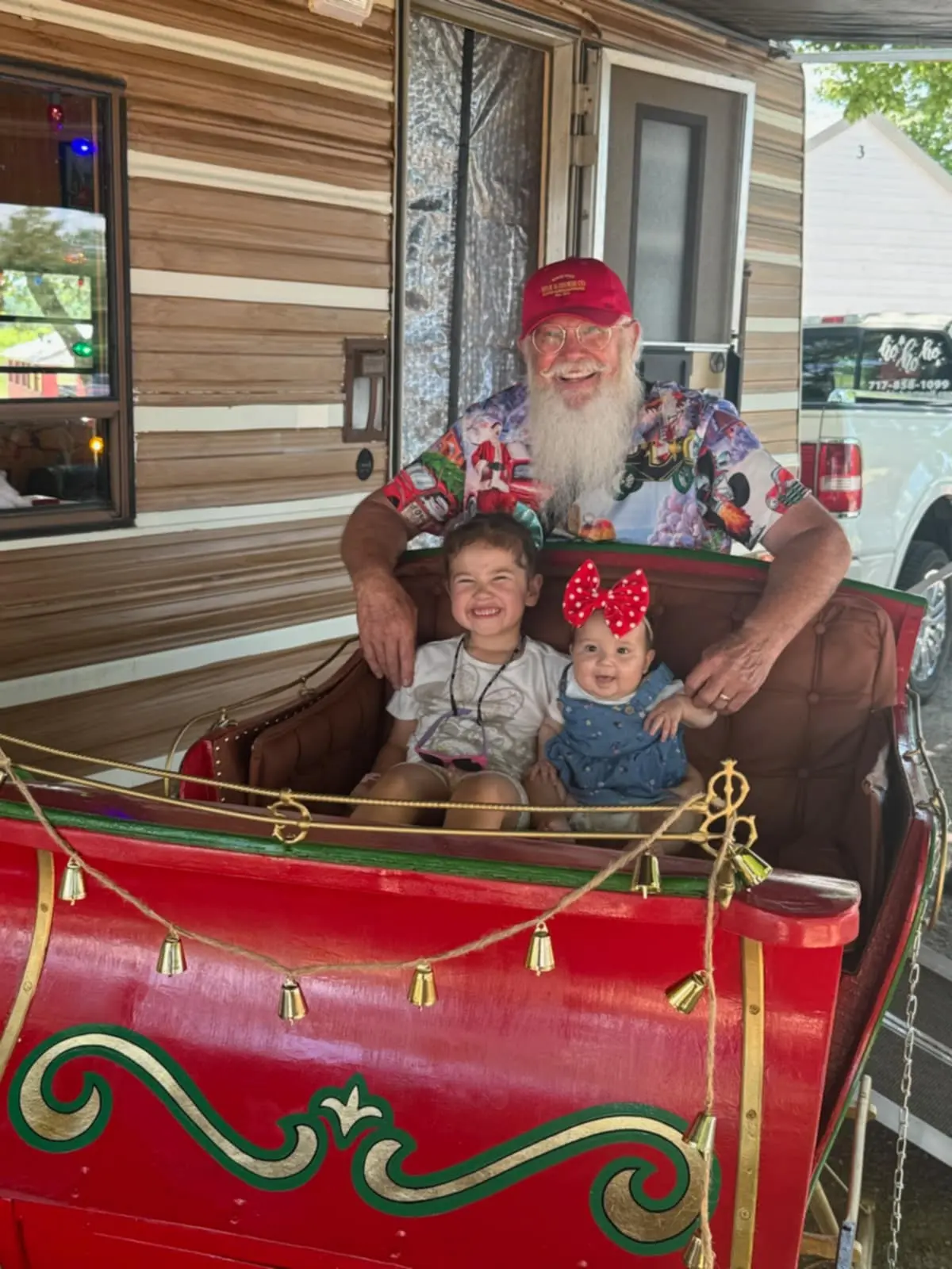 Santa Skip sharing his red and gold sleigh with two smiling children